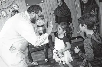  ?? Josie Norris ?? Osama Hassan high-fives Huda Nusayr, 4, for her efforts at a bake sale held Friday to raise money for small appliances for the new Victoria Islamic Center.