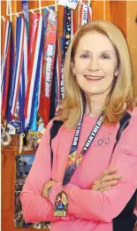  ??  ?? Carol Akright poses with some of the triathlon medals she has won. But it’s the pursuit of good health, she says, not victory, that drives her.