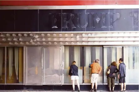  ?? Mark Makela / New York Times ?? Canadian tourists peer into the windows of the now-closed Trump Plaza Casino in Atlantic City, N.J. His other casinos in the struggling seaside resort town — Trump Marina and Trump Taj Mahal — have been sold.