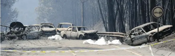  ?? ARMANDO FRANCA / THE ASSOCIATED PRESS ?? Burnt-out cars block the road between Castanheir­a de Pera and Figueiro dos Vinhos on Sunday after wildfires raged through central Portugal.