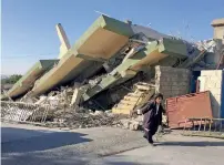  ?? Reuters ?? QUAKE AFTERMATH: A man walks past a damaged building following a quake in Darbandikh­an, Iraq, on Nov 13. —