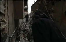  ?? EPA ?? People walk on a destroyed street after air strikes in Mesraba in Eastern Ghouta, which has been bombed several times in recent days by the Assad regime’s forces