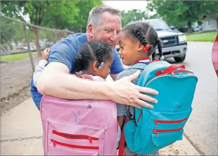  ?? [SARAH PHIPPS PHOTOS/ THE OKLAHOMAN] ?? Principal Mitch Ruzzoli hugs Melody McCauley and Lyric McCauley, 6, goodbye as their parents pick them up on the last day of school Friday at Horace Mann Elementary in Oklahoma City.
