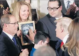 ?? Pablo Martinez Monsivais Associated Press ?? JEANNE MOSER of New Hampshire looks on as President Trump touches a photo of her son, Adam, who died at 27 of an apparent fentanyl overdose.