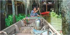  ??  ?? Diver Bhoomin Samang leaving his house in a boat with his homemade metal scuba helmet along Bangkok’s Chao Phraya river.