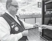  ??  ?? Charles Conn, an assistant manager at the Walmart in Moore, explains how associates load packages into the store’s new Pickup Tower and how customers retrieve their items.