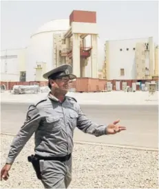  ??  ?? ► Un oficial iraní en frente del complejo nuclear de Bushehr, en agosto de 2010.