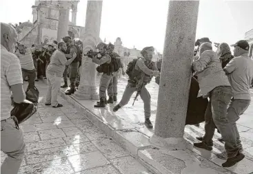  ?? Mahmoud Illean / Associated Press ?? An Israeli police officer aims his weapon at Palestinia­ns during clashes Thursday at the Al-Aqsa Mosque compound in Jerusalem’s Old City.