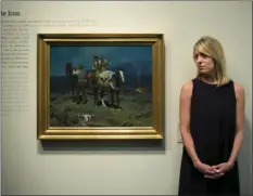  ??  ?? In this Friday photo, chief curator Amy Scott pauses for photos with a painting titled "First Streak of Dawn" by Frank Tenney Johnson at the Autry Museum of the American West, in Los Angeles. AP PHOTO