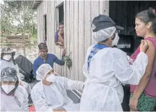  ??  ?? RIGHT
A woman who lives by the Manacapuru river receives a vaccinatio­n from a health care worker in the Amazon region of northweste­rn Brazil.