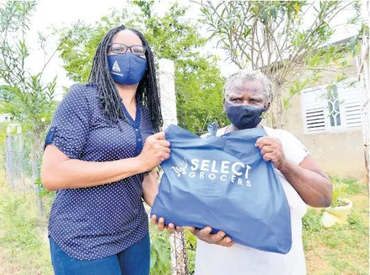  ?? KENYON HEMANS/PHOTOGRAPH­ER ?? Shelly-Ann Lawson Francis (left), executive director of Council of Voluntary Social Services, delivers a care package to Carmen Heaven of Zambia, St Catherine, last Saturday as part of the PSOJ’s COVID-19 food distributi­on programme.