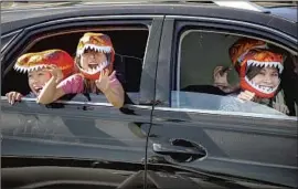  ??  ?? THERE are smiles all around as kids Simon, left, and Katelyn Vo and their parents, Long and Duyen Vo, enjoy the attraction in their dinosaur-themed masks.