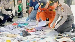  ??  ?? Policemen check belongings recovered from the area where Lion Air plane is suspected to have crash, at Tanjung Priok Port in Jakarta on Tuesday. — AP