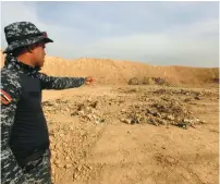  ?? (Alaa al-Marjani/Reuters) ?? A MEMBER OF Iraqi security forces gestures towards a mass grave for corpses in the town of Hammam al-Alil which was seized from Islamic State last week,