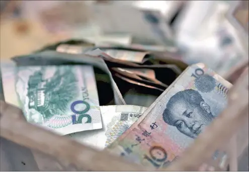  ?? PHOTO: REUTERS ?? Chinese banknotes are seen in a vendor’s cash box at a market in Beijing. The writer says the country’s approach of springing monetary surprises is not helpful.