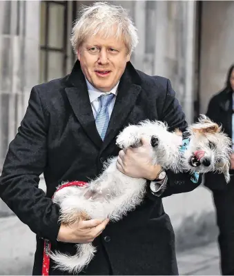  ?? PHOTO: REUTERS ?? Dog day afternoon: Britain’s Prime Minister Boris Johnson holds his dog Dilyn as he leaves a polling station at the Methodist Central Hall in London yesterday.