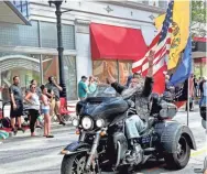  ?? MICHAEL SEARS / MILWAUKEE JOURNAL SENTINEL ?? David Zien, former Wisconsin state senator for the 23rd Senate District, waves to the crowd as he passes by on his three-wheeled Harley-Davidson motorcycle with full-size American and Wisconsin flags. Zien has logged more than 2 million miles riding motorcycle­s, and lost part of his left leg in a highway crash in Florida.