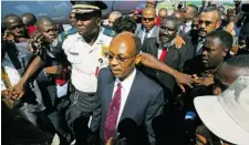  ?? HECTOR RETAMAL/ AFP/GETTY IMAGES ?? Jean-Bertrand Aristide is escorted by security in Port-au-Prince in March 2011 after seven years of exile in South Africa.