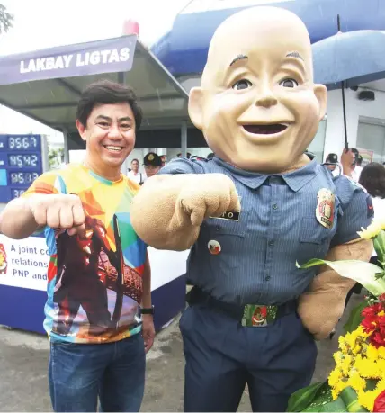  ?? JOY TORREJOS ?? Barangay Captain Junard “Ahong” Chan of Pajo, Lapu-Lapu City joins the PNP mascot in a souvenir photo while flashing their clenched fists.