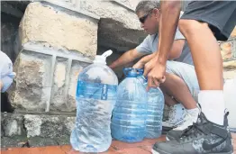  ?? Picture: AFP ?? GOING UNDERGROUN­D. People collect drinking water from pipes fed by an undergroun­d spring, in Cape Town.