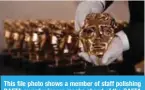  ??  ?? This file photo shows a member of staff polishing BAFTA award winners masks ahead of the BAFTA British Academy Film Awards at the Royal Albert Hall in London. — AFP