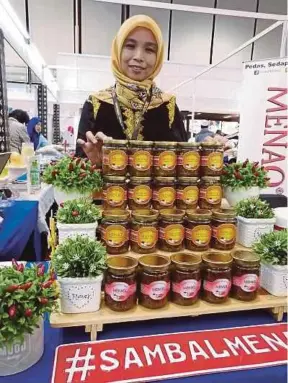  ??  ?? Zarinah bersama rangkaian produk sambal MENAQ milik syarikatny­a.