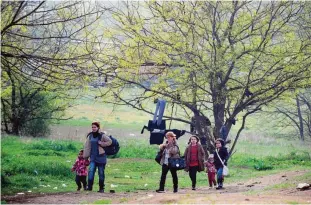  ??  ?? TOMPA, Hungary: Syrians carry their belongings through the forest near the Hungarian border fence at the Tompa border station transit zone as the Hungarian Interior Minister Sandor Pinter (not pictured) presented the camp to the media. —AFP