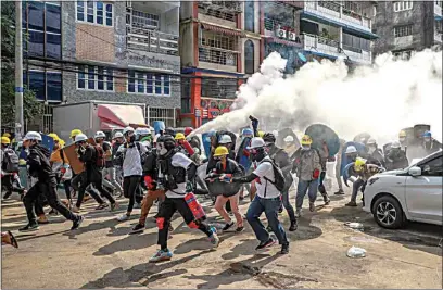  ?? PHOTOS BY THE ASSOCIATED PRESS ?? Anti-coup protesters run as one of them discharges a fire extinguish­er to counter the impact of tear gas fired by riot policemen Wednesday in Yangon, Myanmar.