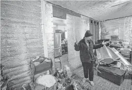  ?? Jon Shapley / Houston Chronicle ?? A woman walks through the flood-damaged living room of her home, where she was still living months after Hurricane Harvey . “I lost everything,” she said of the storm. A church donated drywall to help with repairs.