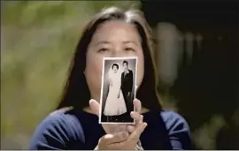  ?? Myung J. Chun Los Angeles Times ?? LORI MATSUMURA holds a photo of parents Kyoko and Masaru Matsumura. Japanese American groups urged EBay to halt bids for her father’s drawings.