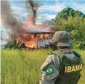  ?? IBAMA ?? An agent with Brazil’s environmen­tal agency watches as a structure and plane belonging to miners burn Monday in the Yanomami Indigenous territory, Roraima state, Brazil.