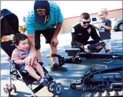  ?? NEWS-SENTINEL FILE PHOTOGRAPH ?? Liam Corralejo of Stockton, left, with grandpa Craig Huft, of Lodi, is not sure what to think of the bomb robot, driven by Lodi police officer Austin Blythe (second from right), who is showing John Barkely, 3, the controls during National Night Out in 2017.
