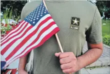  ?? MIKE KNAAK
THE ASSOCIATED PRESS ?? A Pakistani recruit, 22, who was recently discharged from the U.S. army holds an American flag. The man asked his name to be undisclose­d.