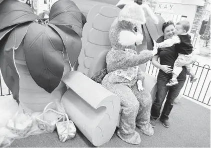  ?? BRIAN KRISTA/BALTIMORE SUN MEDIA GROUP ?? Whitney Griggs of Whiteford holds her 20-month-old son, Brayden, as he greets the Easter Bunny with a high five at the Harford Mall.