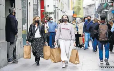  ?? MARILÚ BÁEZ ?? Varias personas con bolsas por la calle Nueva.