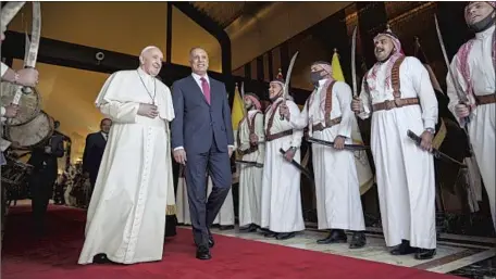  ?? Ayman Henna AFP/Getty Images ?? walks with Iraqi Prime Minister Mustafa Kadhimi after arriving at Baghdad Internatio­nal Airport amid a massive security presence. Before 2000, the country’s Christian population was as large as 1.4 million; it has since dwindled to 250,000.