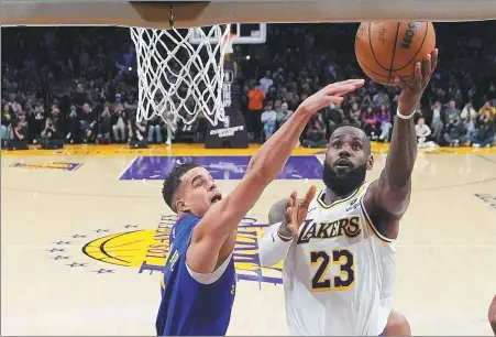  ?? AP ?? LeBron James rises over Michael Porter Jr to score a layup that saw James become the first NBA player to reach 40,000 regular-season points. James’ Los Angeles Lakers, however, lost the game, 124-114, to the Denver Nuggets.