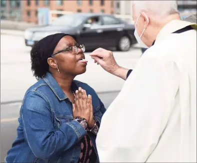  ?? Tyler Sizemore / Hearst Connecticu­t Media ?? The Rev. Albert Audette delivers the Eucharist on the top of the Bell Street Garage across the street from the Basilica of Saint John the Evangelist in Stamford last May. Starting March 19, Connecticu­t churches, mosques, temples and other house of worship will no longer be required to cap the number of people who attend in-person services.