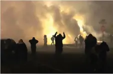  ?? — AFP photo ?? People take cover as police fire tear gas in front of the Brooklyn Center Police Station.