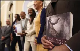  ?? RICH PEDRONCELL­I — THE ASSOCIATED PRESS FILE ?? Dr. Amos C. Brown Jr., vice chair for the California Reparation­s Task Force, right, holds a copy of the book Songs of Slavery and Emancipati­on as he and other members of the task force pose for photos at the Capitol in Sacramento on June 16.