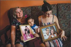  ?? (AP/Ramon Espinosa) ?? Danmara Triana (from left) with her daughters Alice and Claudia show photos May 19 of themselves with their brother and father, who moved to the United States in 2015, at their home in Cienfuegos, Cuba.