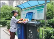  ?? WANG ZHUANGFEI / CHINA DAILY ?? An employee demonstrat­es how to sort household waste at the Yilianxuan residentia­l community.
