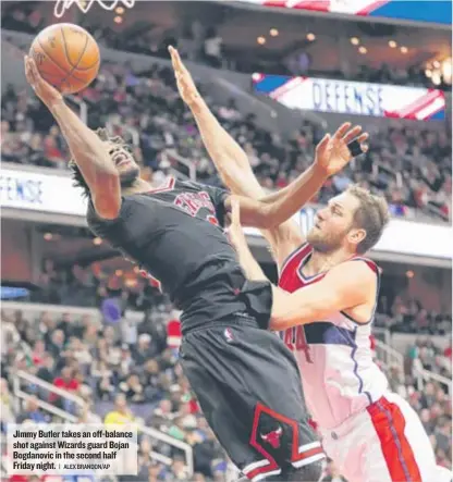  ??  ?? Jimmy Butler takes an off- balance shot against Wizards guard Bojan Bogdanovic in the second half Friday night.