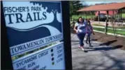  ?? DIGITAL FIRST MEDIA FILE PHOTO ?? Park-goers are seen past a sign for the trails at Fischer’s Park in Towamencin Township.