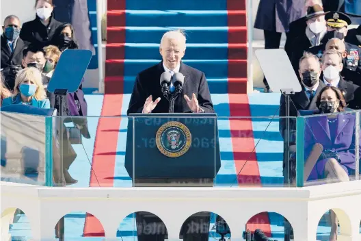  ?? PATRICK SEMANSKY/GETTY-AFP ?? President Joe Biden, flanked by first lady Jill Biden, left, and Vice President Kamala Harris, right, delivers his Inaugurati­on speech after being sworn in on Wednesday in Washington, just two weeks after the nation’s Capitol had been battered by an insurrecti­onist siege and amid a pandemic that has killed more than 400,000 Americans.