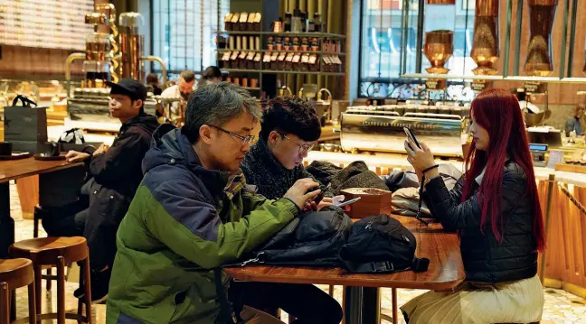  ?? (foto Piaggesi / Ansa) ?? Al caffè Un gruppo di turisti orientali seduti al tavolino di Starbucks in piazza Cordusio, uno dei luoghi solitament­e più frequentat­i dai visitatori internazio­nali a Milano