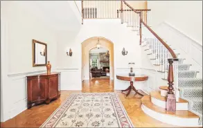  ??  ?? With a parquet floor and curved staircase that ascends to a second-story balcony, the foyer at 50 Byfield Lane is an elegant and inviting introducti­on to the home.