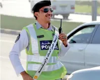  ?? Supplied photo ?? First sergeant Sameer Abdullah stands in the middle of a road in RAK, wearing a seatbelt and flashing a smile. —