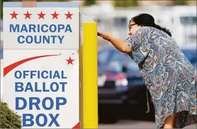  ?? Matt York / Associated Press ?? A voter drops off her ballot at a drop box on Nov. 7 in Mesa, Ariz. Fears of aggressive poll watchers sowing chaos at polling stations or conservati­ve groups trying to intimidate votes didn't materializ­e on Election Day as many election officials and voting rights experts had feared. Voting proceeded smoothly across most of the U.S., with a few exceptions of scattered disruption­s.