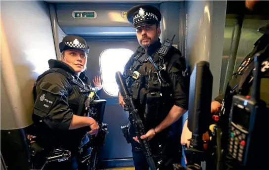 ?? PHOTO: REUTERS ?? Armed police officers stand guard in a train at Milton Keynes station yesterday. Armed police are patrolling trains across Britain for the first time, following the Manchester suicide bombing.